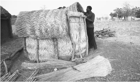 A man builds a small granary from wood and straw for his village in Ghana. The country&#x0027;s economy is primarily agricultural.